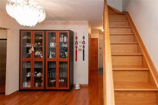 stairway featuring an inviting chandelier, baseboards, and wood finished floors