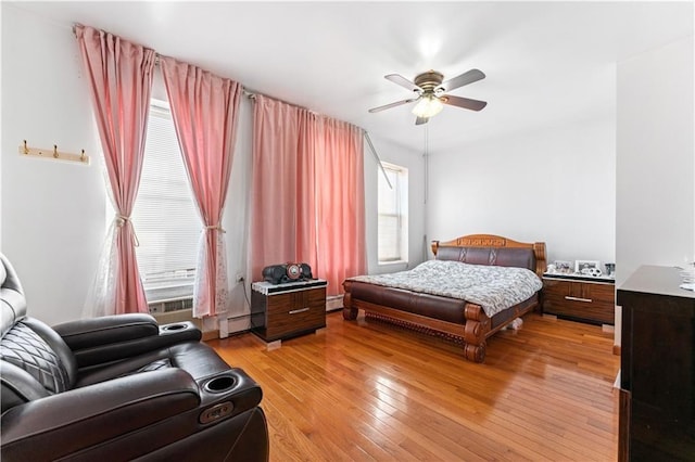 bedroom with light wood-style floors, baseboard heating, and a ceiling fan