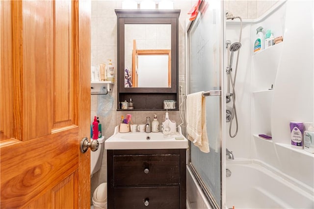 bathroom featuring tile walls, combined bath / shower with glass door, backsplash, and vanity