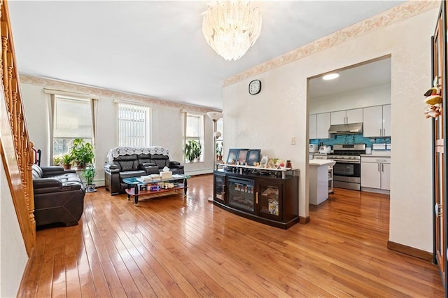 living room featuring light wood-style floors, baseboards, and a notable chandelier