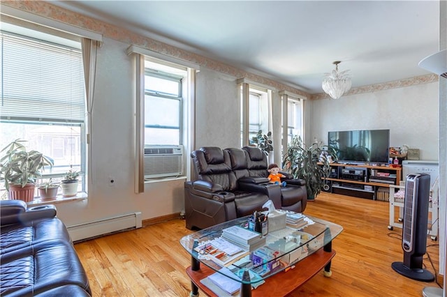 living area with baseboards, baseboard heating, wood finished floors, and an inviting chandelier