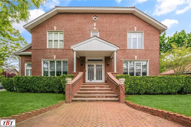 view of front facade with entry steps, french doors, a front lawn, and brick siding