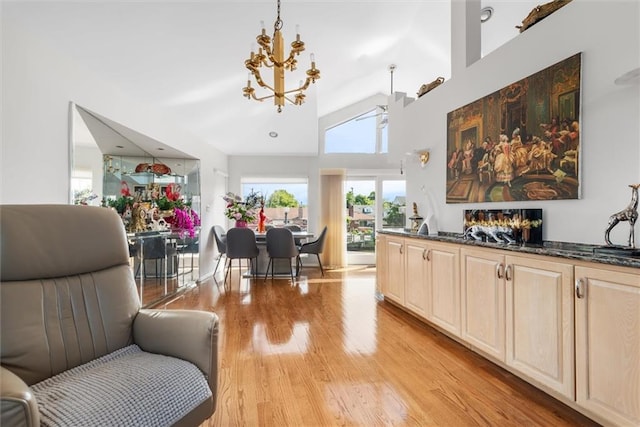 interior space with decorative light fixtures, high vaulted ceiling, a notable chandelier, dark stone counters, and light hardwood / wood-style floors