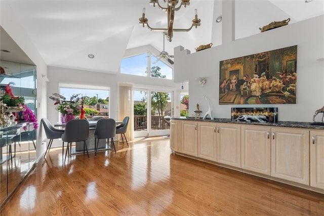 interior space featuring high vaulted ceiling, ceiling fan with notable chandelier, and light hardwood / wood-style flooring