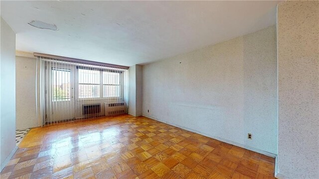 spare room featuring radiator heating unit and light parquet flooring