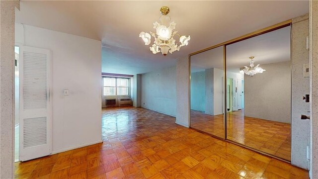 spare room with light parquet flooring and an inviting chandelier