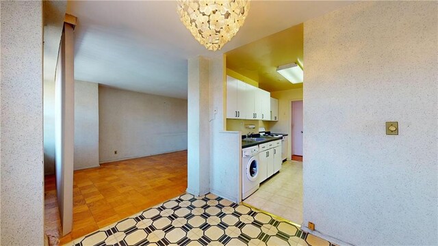 kitchen featuring white cabinets, washer / dryer, and a chandelier