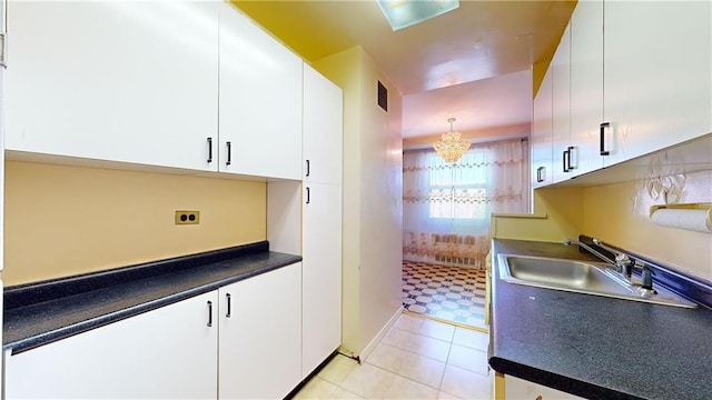 kitchen featuring light tile patterned floors, a sink, visible vents, white cabinetry, and dark countertops