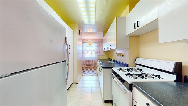 kitchen featuring white appliances, an inviting chandelier, white cabinets, sink, and light tile patterned flooring