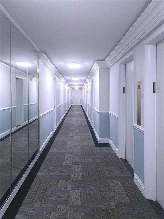 hallway with elevator and crown molding