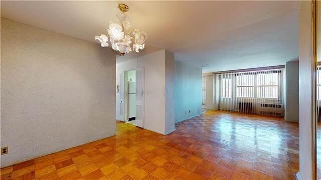 unfurnished room featuring parquet flooring and an inviting chandelier