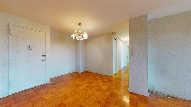 spare room with a notable chandelier and light parquet floors