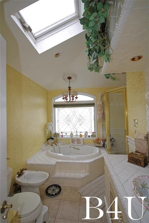 bathroom with tile patterned flooring, a garden tub, a skylight, and toilet