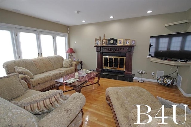 living area featuring visible vents, baseboards, recessed lighting, wood finished floors, and a glass covered fireplace