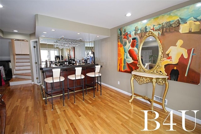 bar featuring stairway, bar, baseboards, and wood finished floors