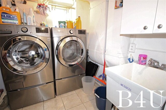 laundry area featuring washer and clothes dryer, sink, light tile patterned floors, and cabinets