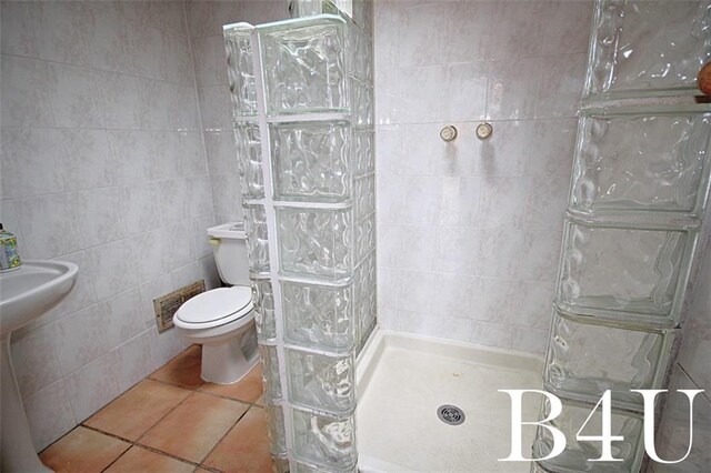 bathroom with walk in shower, tile patterned floors, tile walls, and toilet