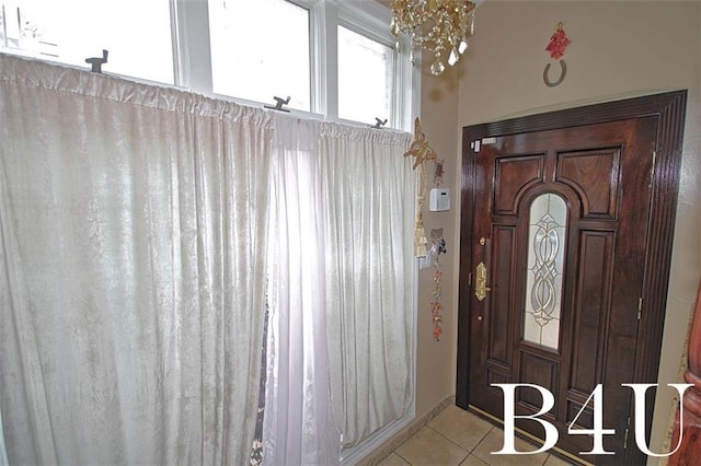 entryway with a chandelier and light tile patterned floors