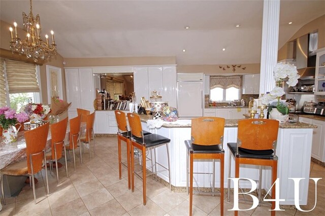 kitchen with light tile patterned flooring, paneled fridge, white cabinetry, and an inviting chandelier