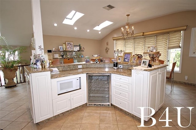 kitchen featuring white microwave, visible vents, beverage cooler, lofted ceiling, and light tile patterned floors