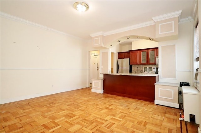 kitchen featuring crown molding, baseboards, light countertops, a peninsula, and stainless steel appliances