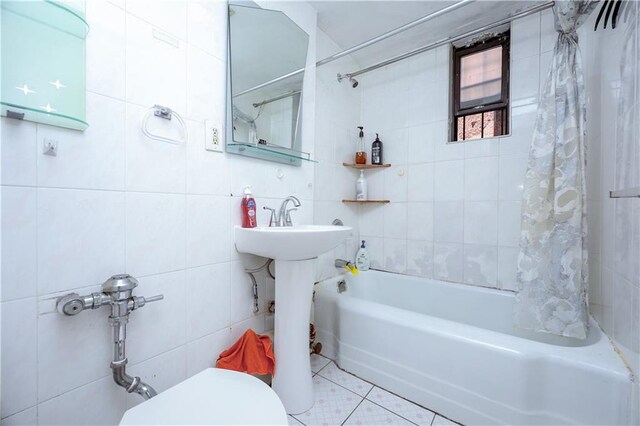 bathroom featuring tile patterned flooring, shower / tub combo with curtain, tile walls, and toilet