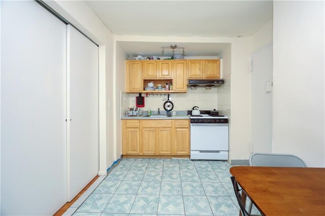 kitchen featuring decorative backsplash, light brown cabinets, white range with gas cooktop, and sink