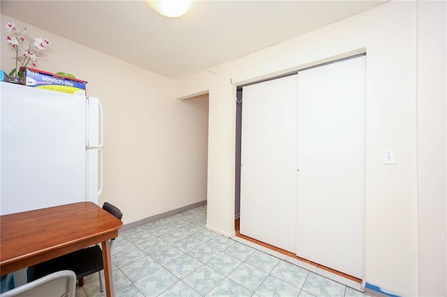 interior space with a closet, freestanding refrigerator, and baseboards