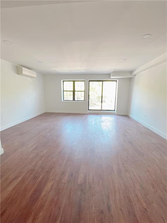 spare room featuring a wall unit AC and wood-type flooring