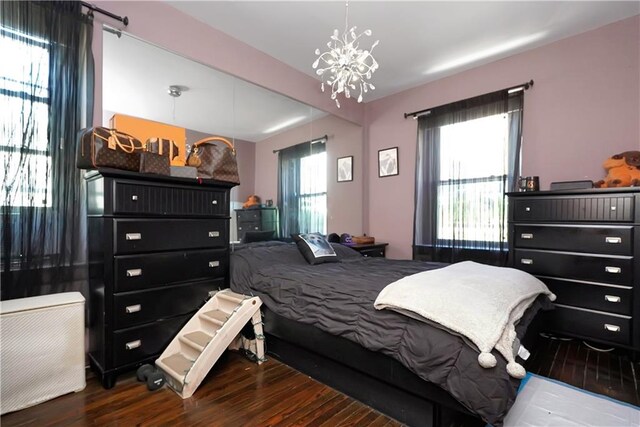 bedroom with multiple windows, an inviting chandelier, and dark hardwood / wood-style flooring