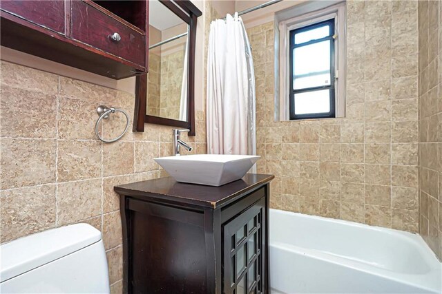 full bathroom featuring vanity, tile walls, toilet, and shower / bath combo with shower curtain