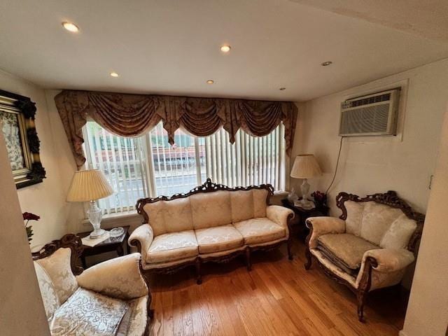 living area with an AC wall unit and wood-type flooring