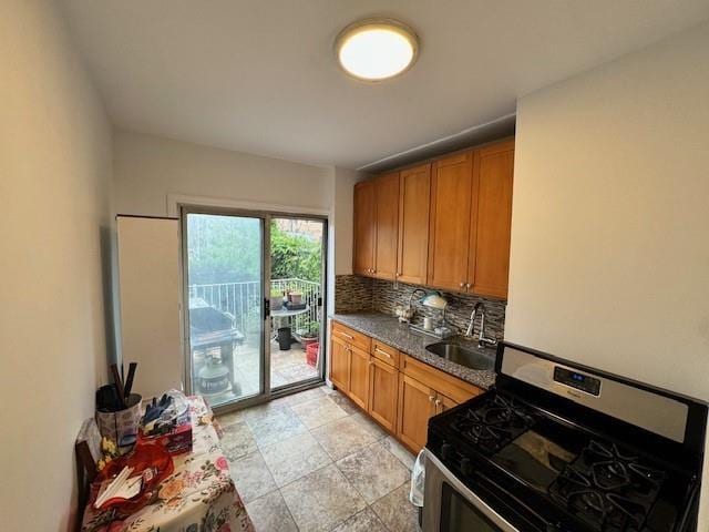 kitchen featuring decorative backsplash, sink, dark stone countertops, and stainless steel range with gas cooktop