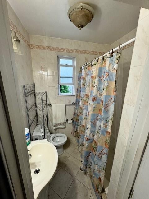 bathroom with sink, curtained shower, tile walls, tile patterned flooring, and toilet