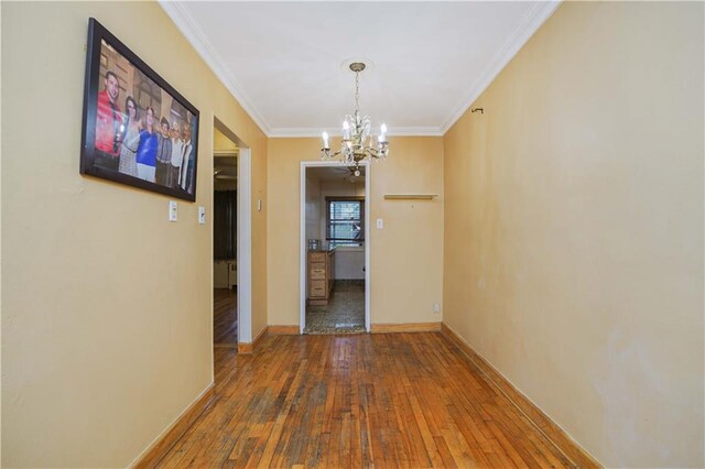 corridor featuring a chandelier, crown molding, and wood-type flooring