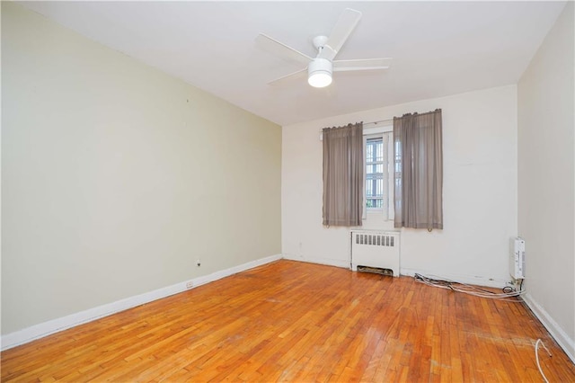 empty room with hardwood / wood-style flooring, radiator, and ceiling fan