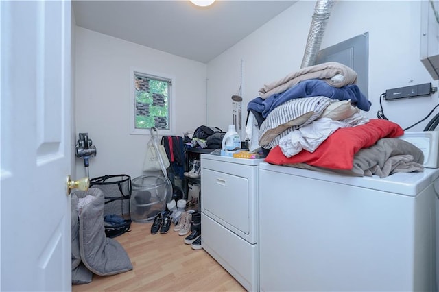 clothes washing area with cabinets, independent washer and dryer, and light hardwood / wood-style flooring