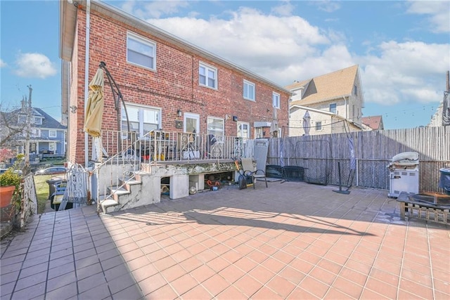 back of house featuring a patio area, brick siding, and fence