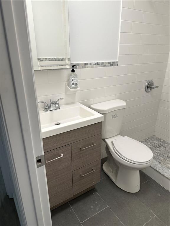 bathroom featuring backsplash, vanity, tile patterned floors, toilet, and walk in shower