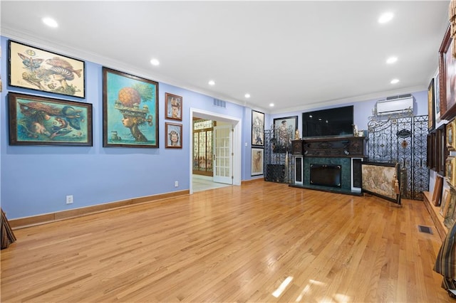 unfurnished living room featuring ornamental molding, light hardwood / wood-style floors, and a wall mounted air conditioner