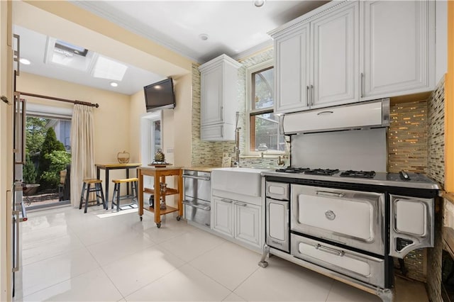 kitchen featuring tasteful backsplash, crown molding, light tile patterned floors, and white cabinets