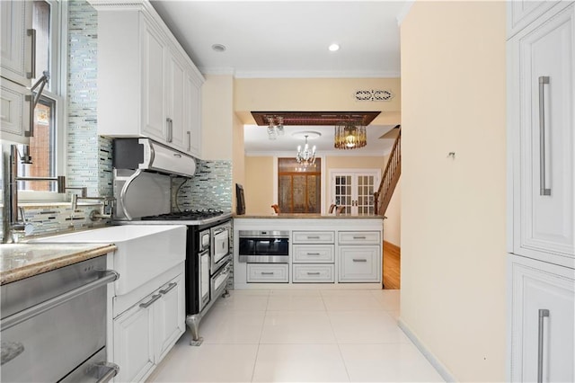 kitchen featuring appliances with stainless steel finishes, white cabinets, backsplash, kitchen peninsula, and crown molding