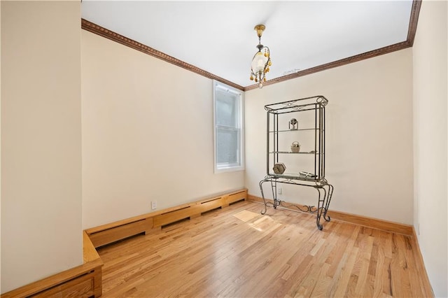 empty room featuring a baseboard radiator, wood-type flooring, a chandelier, and crown molding