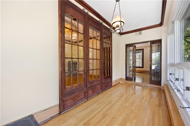 doorway featuring light hardwood / wood-style flooring, ornamental molding, and french doors