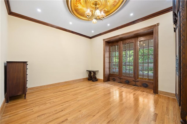 spare room with crown molding, a notable chandelier, and light wood-type flooring