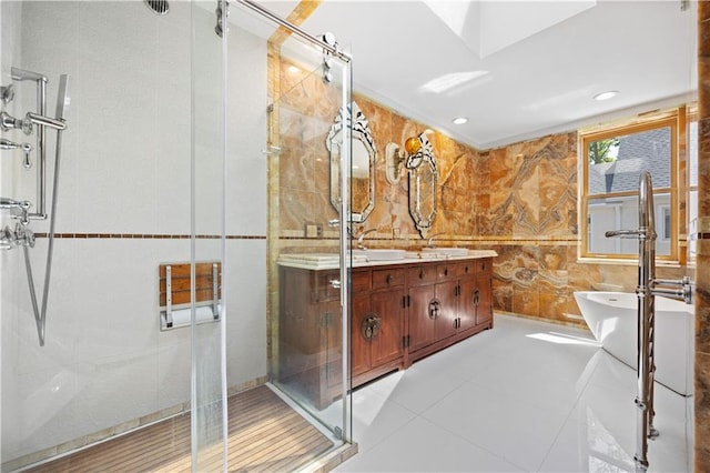 bathroom with a shower with door, vanity, tile patterned flooring, and tile walls