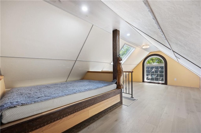 bedroom with wood-type flooring and vaulted ceiling