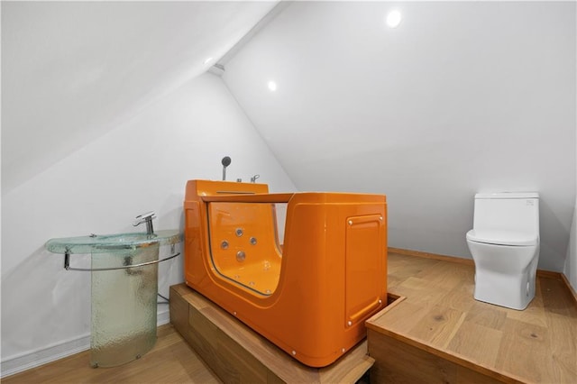 bathroom with vaulted ceiling, separate washer and dryer, hardwood / wood-style floors, and toilet