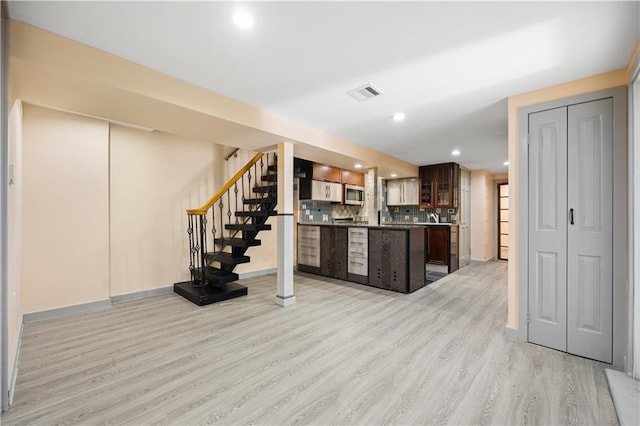 kitchen with dark brown cabinets, light hardwood / wood-style floors, and decorative backsplash