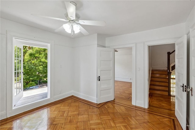empty room with baseboards, ceiling fan, and stairs